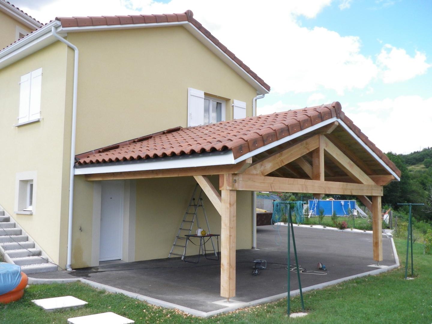 Abri voiture en bois couvert de tuiles accolé à une maison