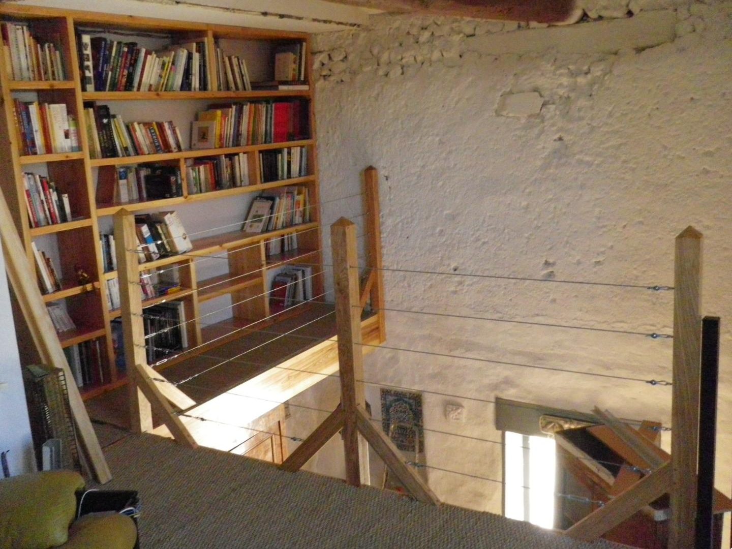Bibliothèque en bois et garde-corps à câbles sur une mezzanine