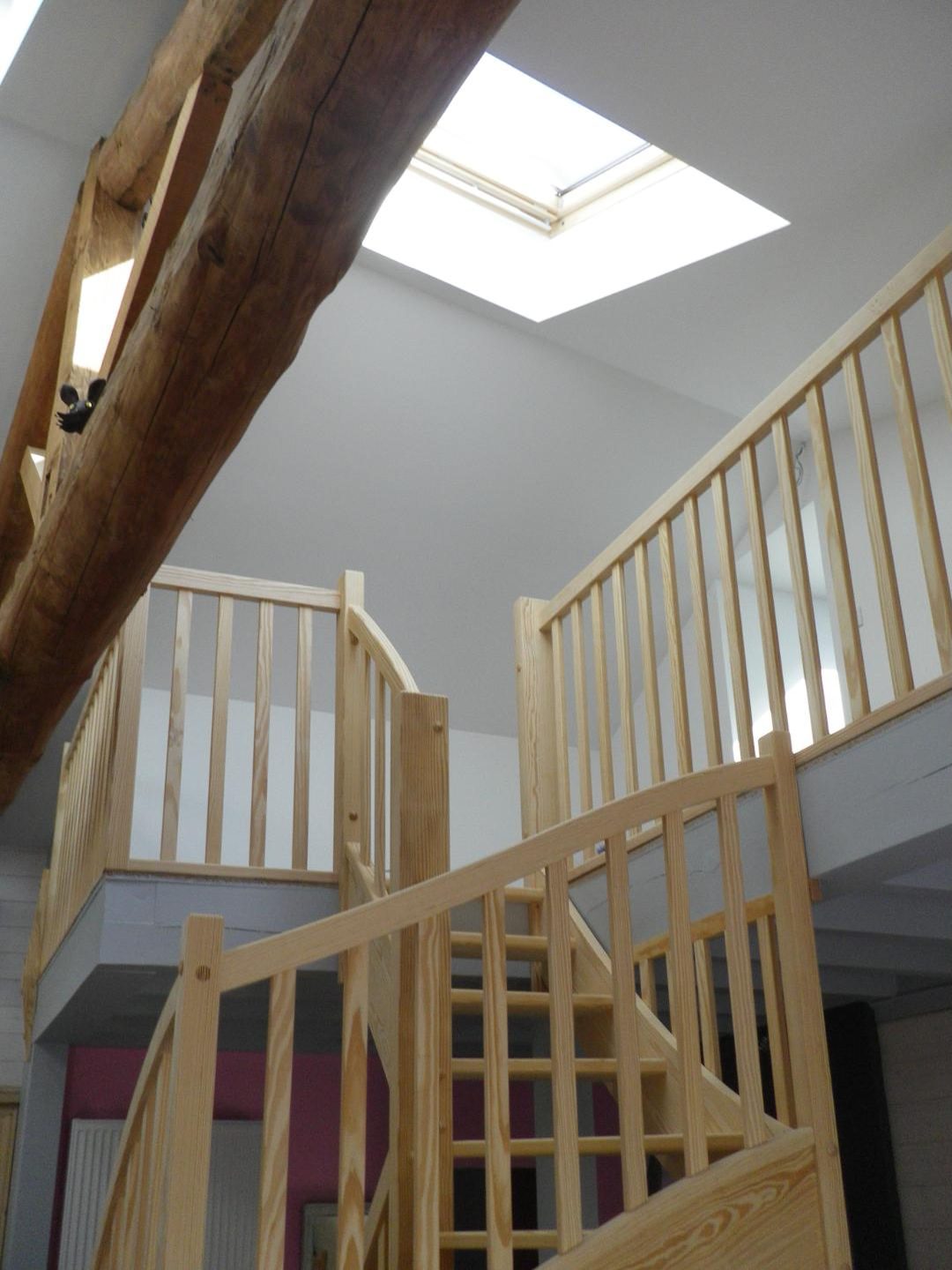 Escalier en bois clair sous une fenêtre de toit