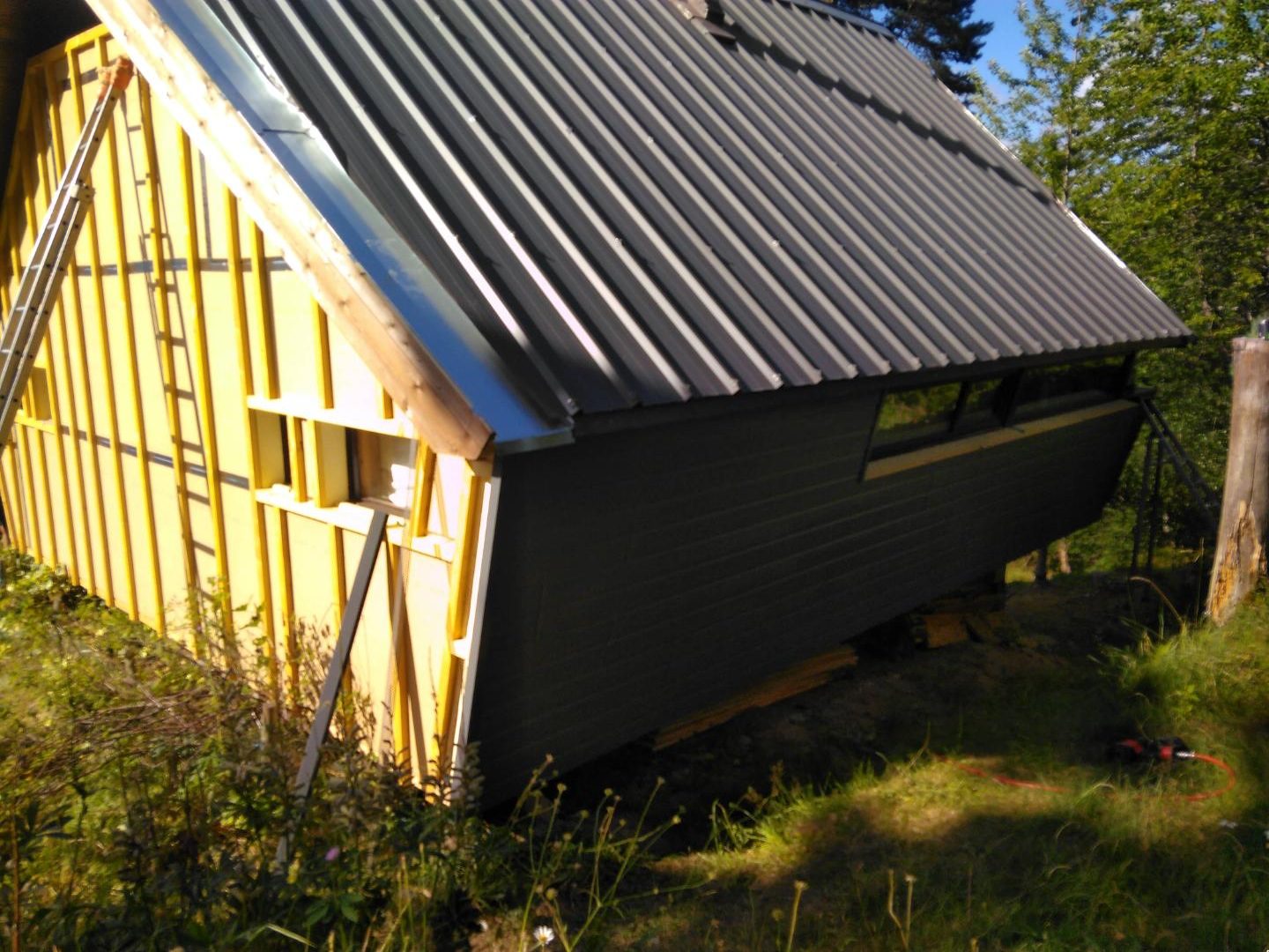 Bâtiment en ossature bois avec panneaux isolants jaunes et bardage sombre