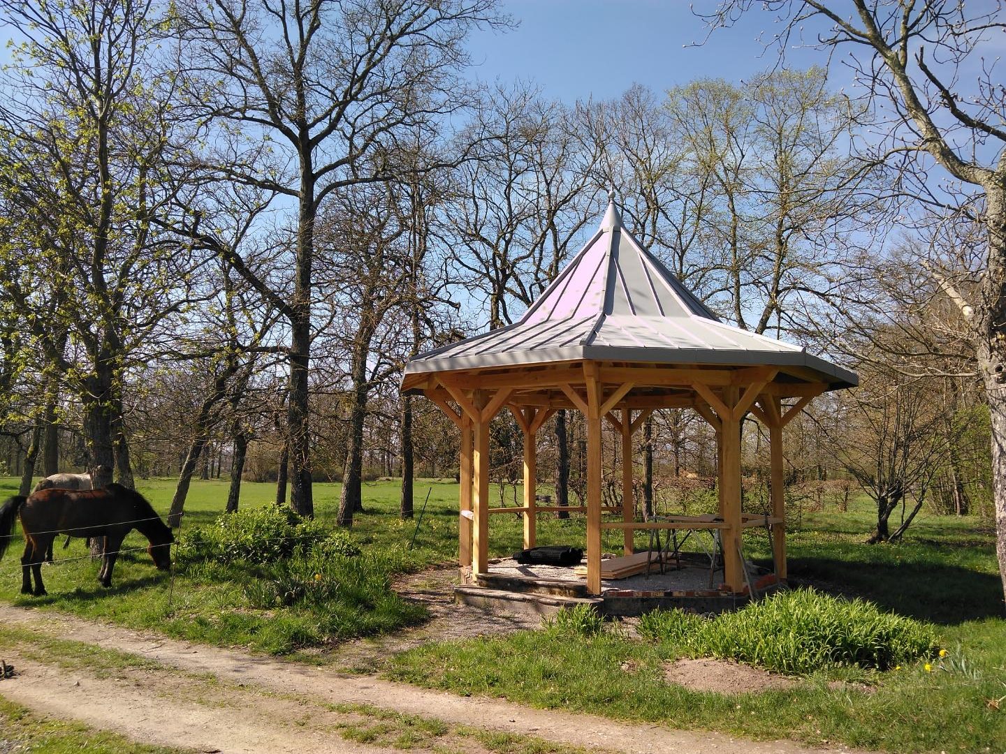 Kiosque octogonal en bois massif dans un parc, couverture métallique grise