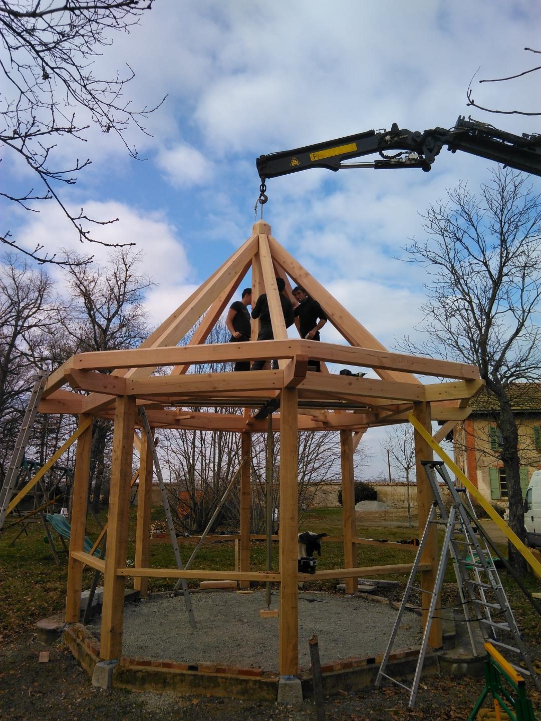 Charpentiers sur la structure d’un kiosque pendant le levage du poinçon