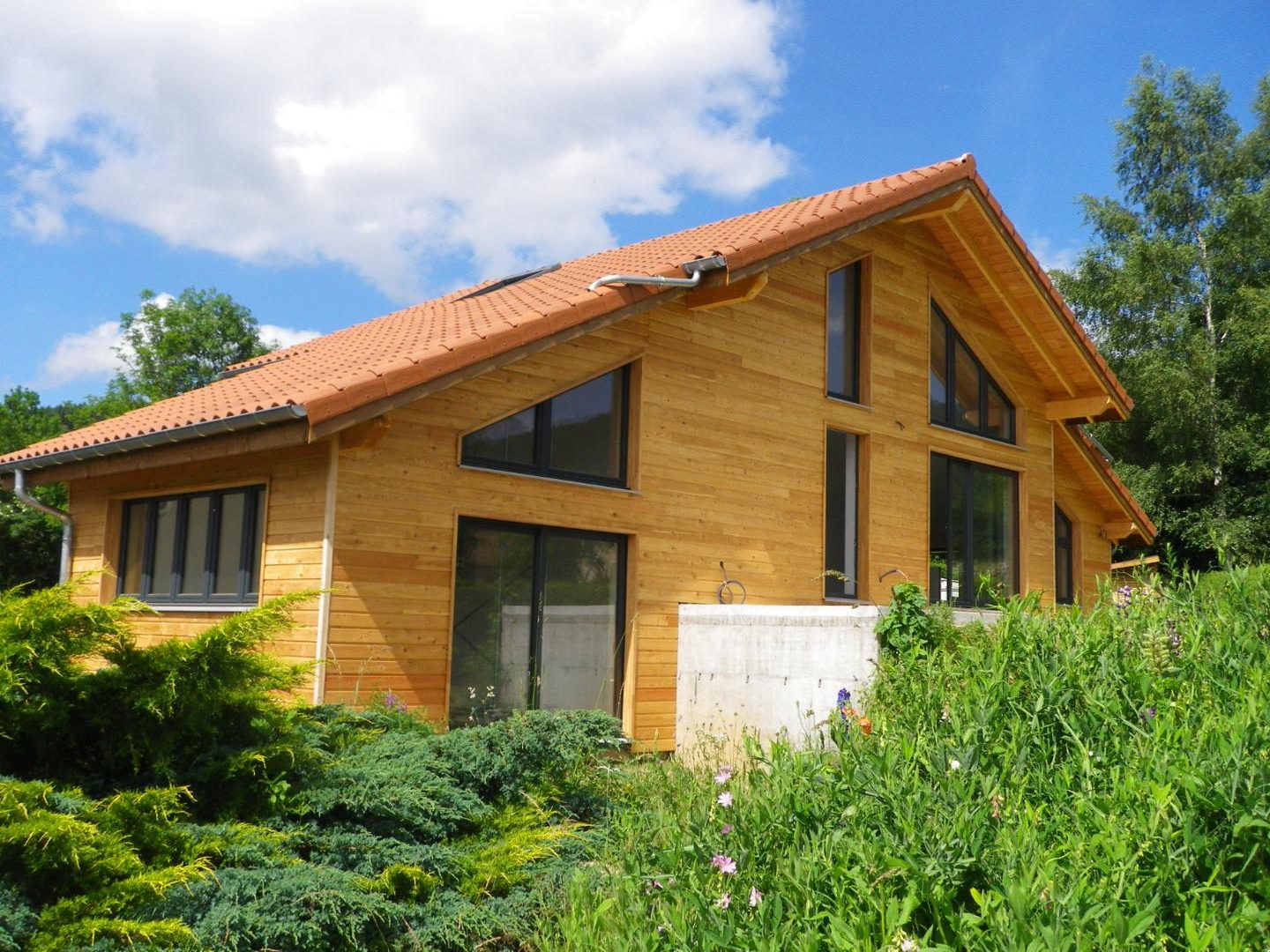 Maison en ossature bois à bardage horizontal clair, grandes baies vitrées