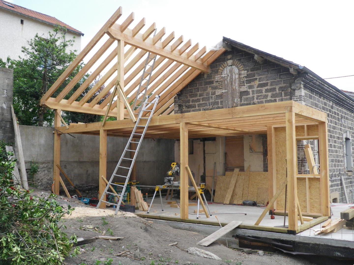 Structure poteaux-poutres et chevrons d’une extension en cours de montage