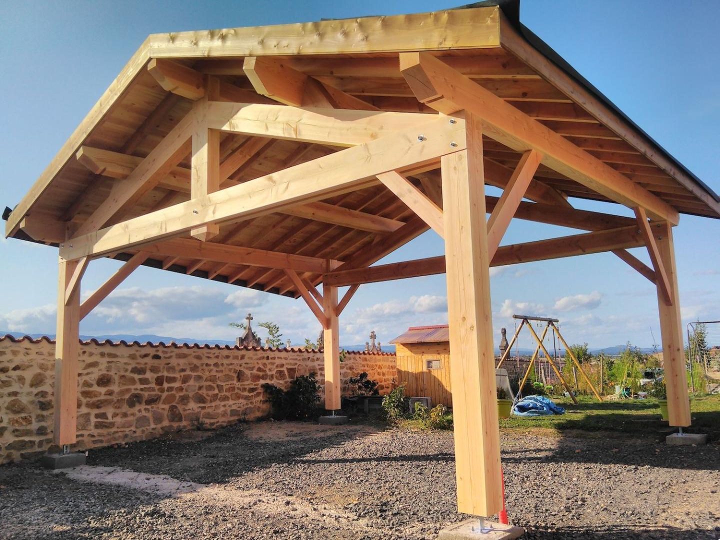 Pergola en bois massif à quatre pans dans un jardin clos de murs en pierre