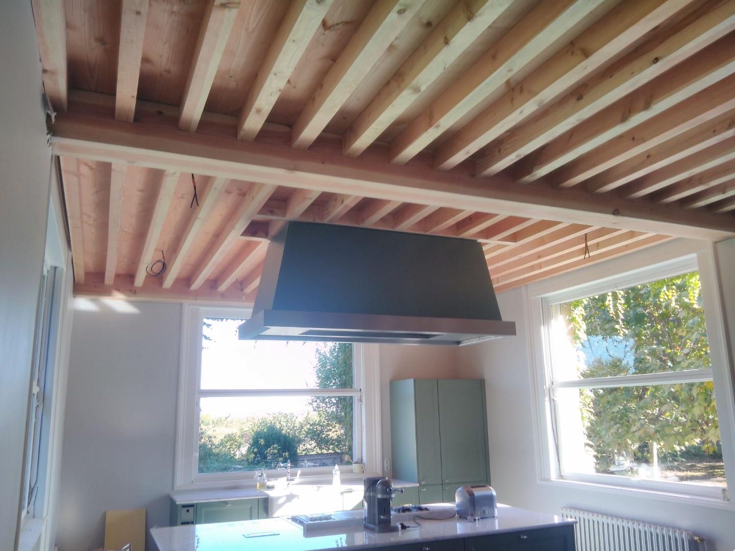 Plafond à solives apparentes au-dessus d’une cuisine lumineuse