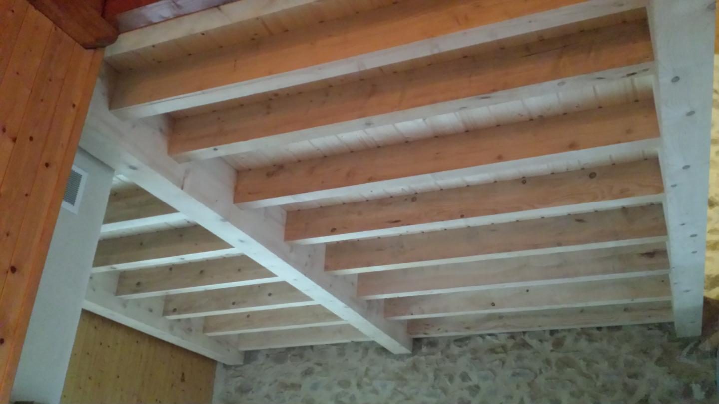 Solivage en bois vu de dessous, poutre maîtresse et mur en pierre